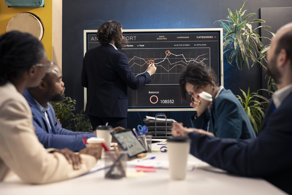Business team analysing data on digital dashboard during a marketing strategy meeting.
