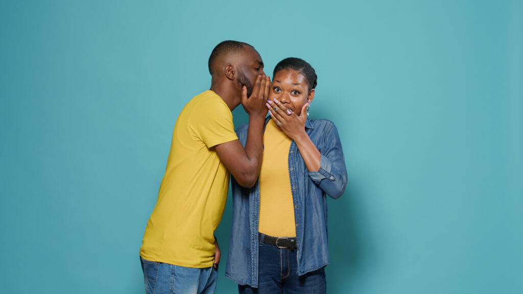 A man whispering words to a woman